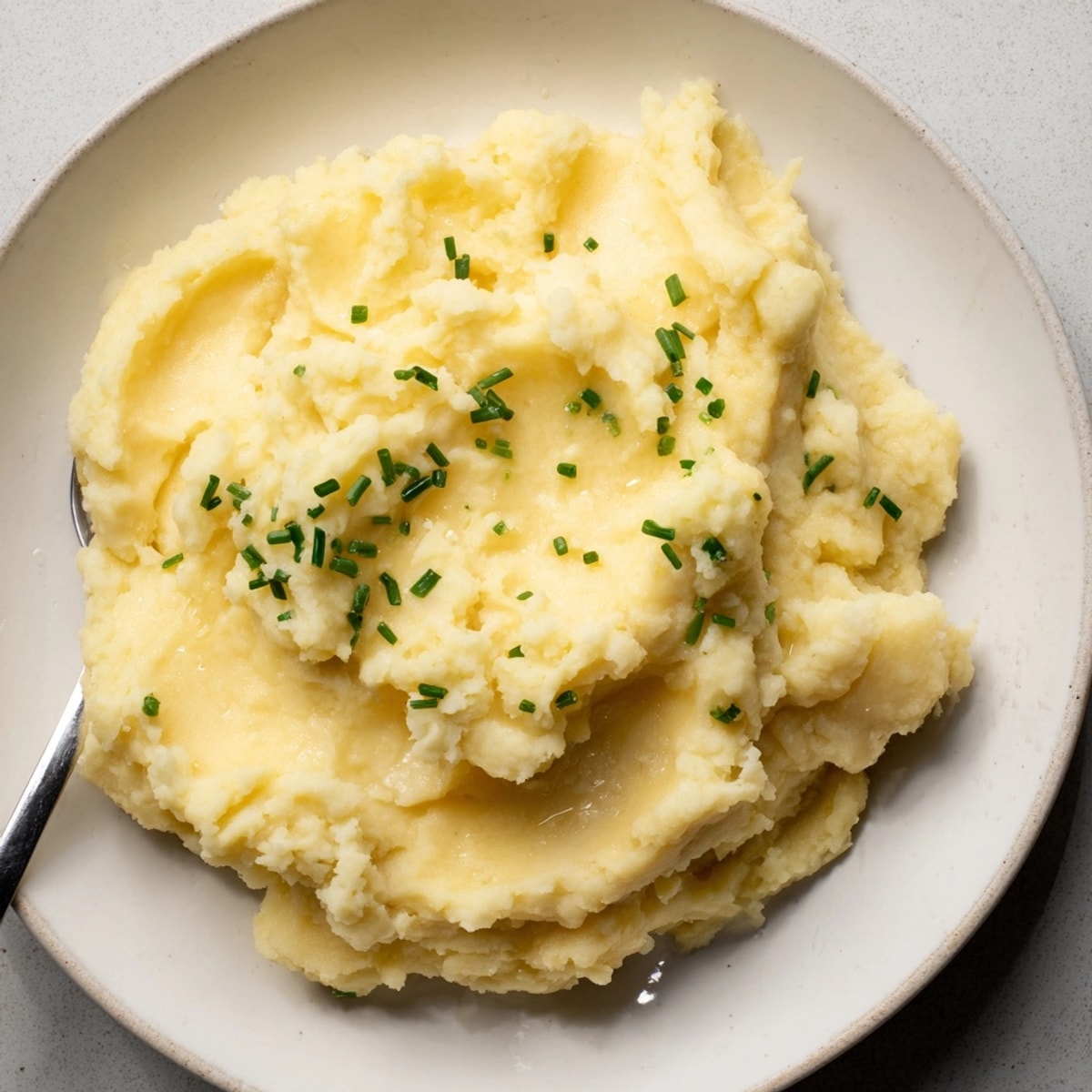 Bowl of creamy Smoked Gouda Mashed Potatoes, garnished with fresh chives and ready to serve.