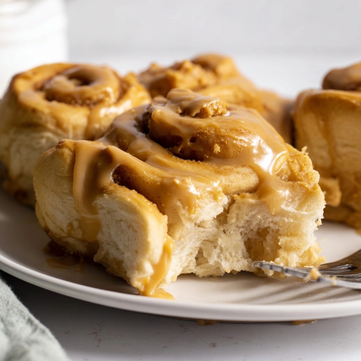 Golden Peanut Butter Maple Breakfast Rolls fresh from the oven drizzled with glaze.