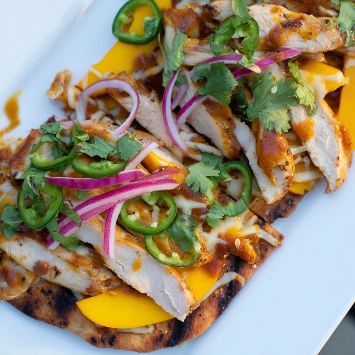 Golden Mango BBQ Chicken Flatbread sizzling hot, bubbly cheese melts, cilantro garnish.