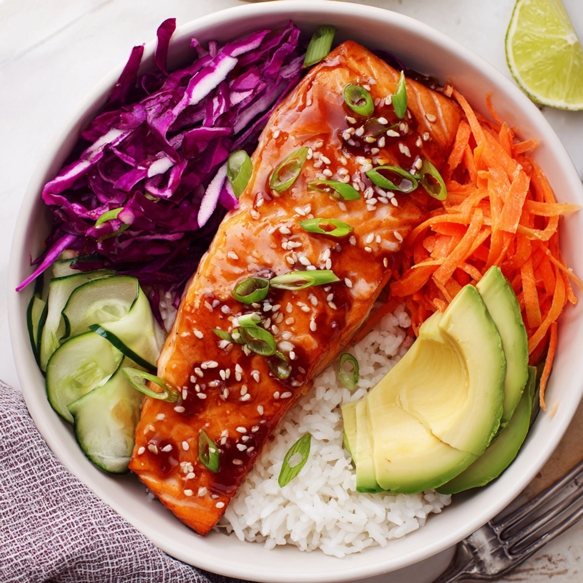 Sweet and savory Soy-Maple Salmon Rice Bowls, picture sesame seeds, green onions, and lime.