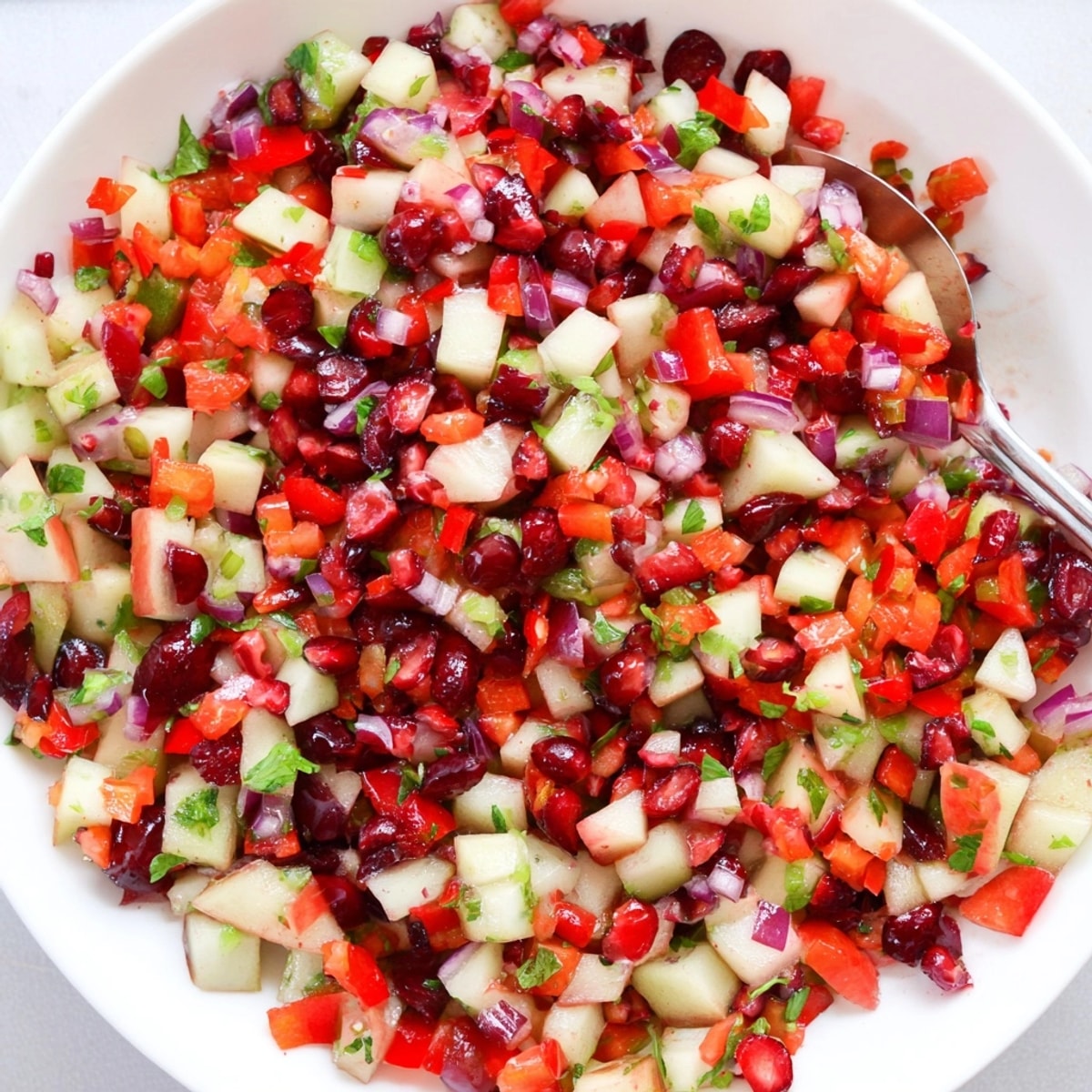 Close-up shows vibrant Pear and Cranberry Jalapeño Salsa in a bowl, ready with chips.