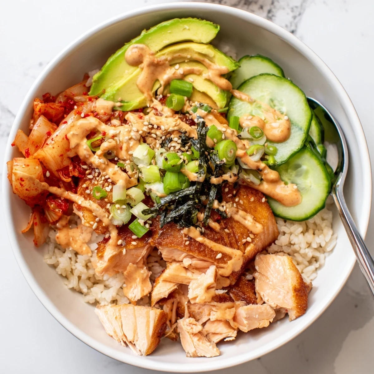 Crispy Salmon Rice Bowl topped with spicy mayo, kimchi, and fresh avocado slices.  