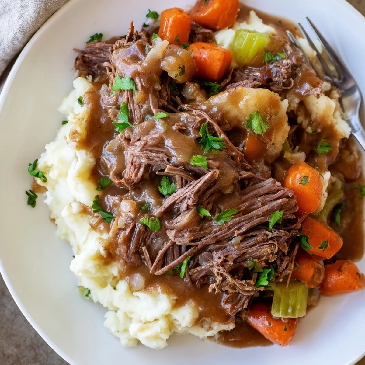 Creamy mashed potatoes complement savory Slow Cooker Pot Roast garnished with fresh parsley.