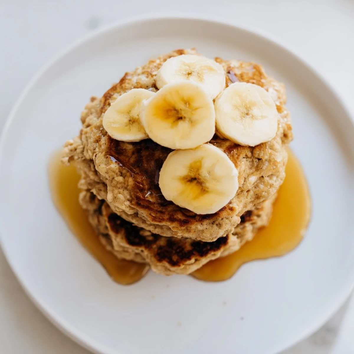 Freshly made, warm banana oat pancakes with visible oats, ready with berries and yogurt.