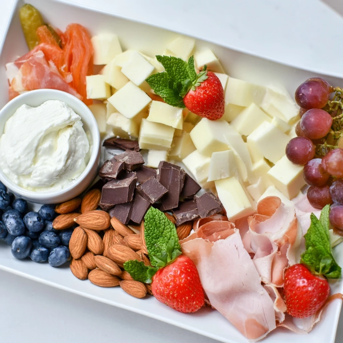 This Gift Box Brunch Board Delight shows a beautiful spread, including mini pastries, cheeses, and berries, ready to eat.
