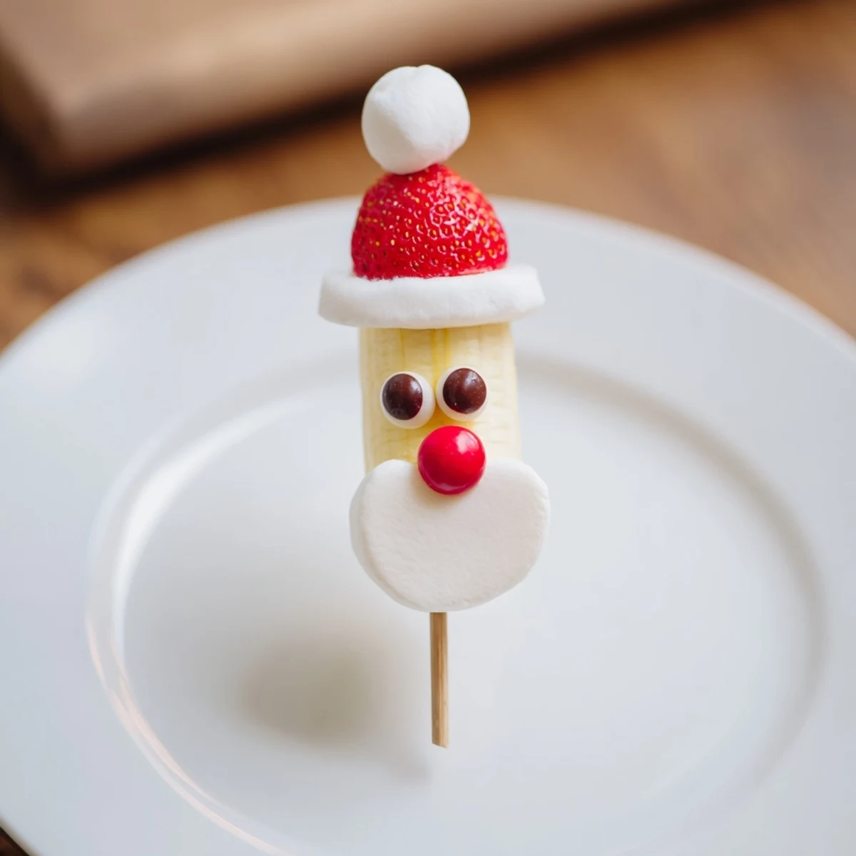 Freshly assembled Banana Santa Snack Sticks with strawberry hats and chocolate chip eyes, perfect for parties.