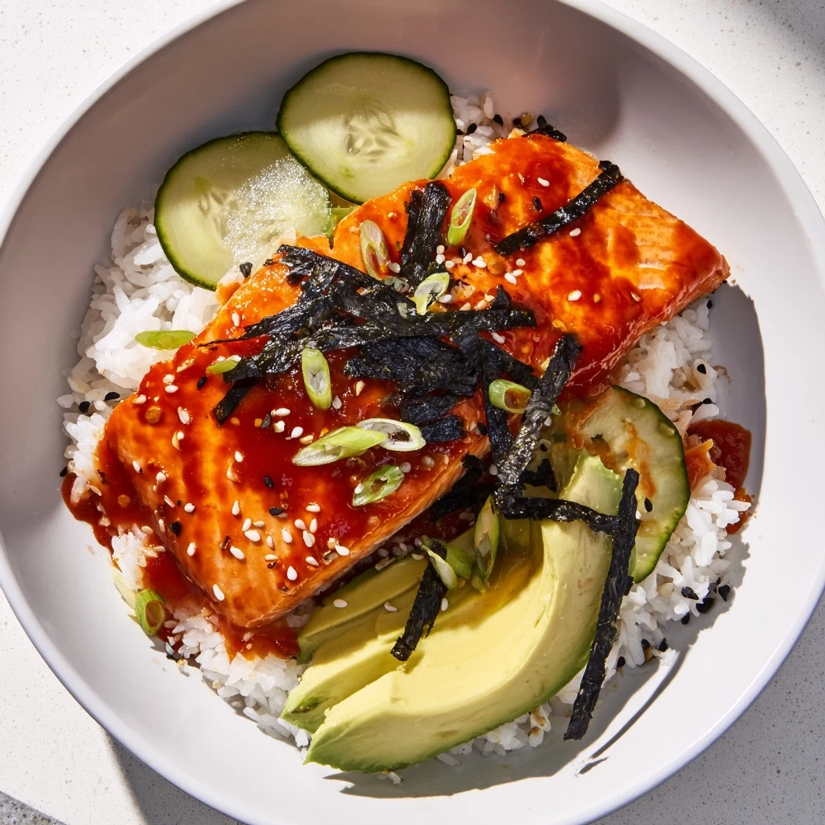Emily Mariko-Inspired Sticky Orange Gochujang Salmon Bowl with glistening glaze and fresh cucumber slices, ready to eat.