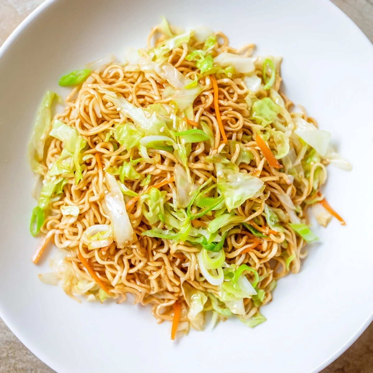 Fried Cabbage Ramen served in a bowl with julienned carrots and a drizzle of sesame oil.