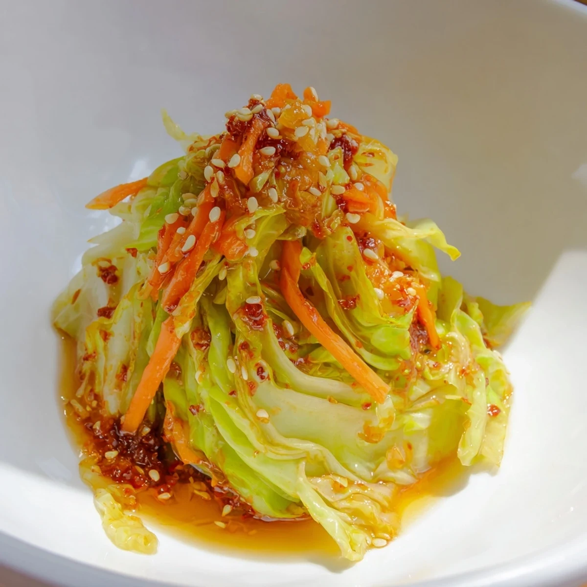 Vibrant bowl of Hot and Sour Cabbage garnished with scallions and sesame seeds, ready to serve as a zesty vegan side dish alongside steamed rice.