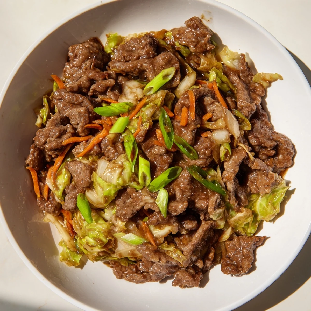 Tender ground beef and crisp shredded cabbage coated in a glossy, umami-rich sauce in a hot wok.  