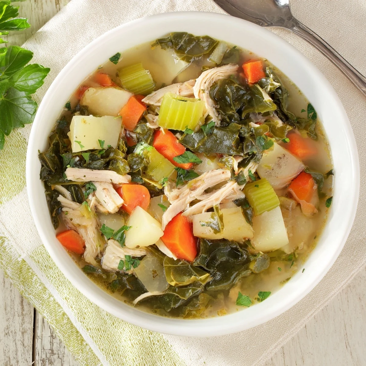 A bowl of Collard Greens, Chicken and Vegetable Soup with tender shredded chicken, creamy potatoes, and bright greens in a golden broth.