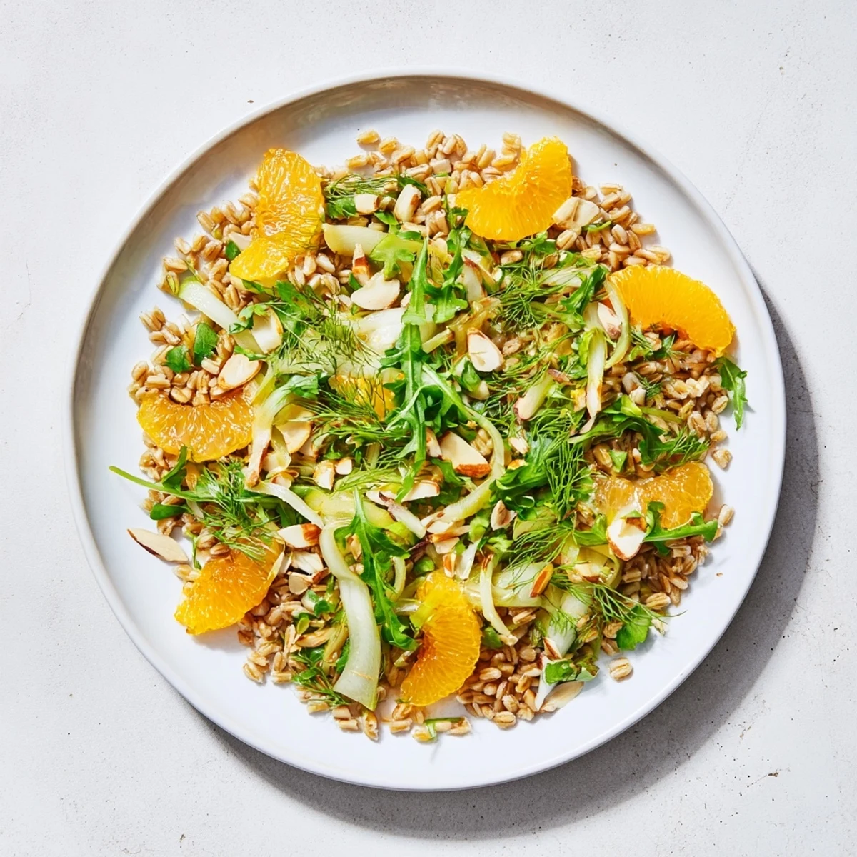 Citrus-scented farro salad featuring crisp fennel, juicy orange slices, toasted almonds, and arugula on a rustic wooden table.  