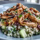 The Asian Sesame Chicken Couscous Salad is tossed with sesame-soy dressing and topped with fresh cilantro, mint, and toasted sesame seeds.