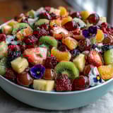 A festive fruit spread featuring a rainbow of fresh produce arranged with edible flowers for a stunning centerpiece.