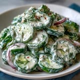 Refreshing summer Creamy Cucumber Dill Salad with red onion slices, perfect for picnics and barbecues.  