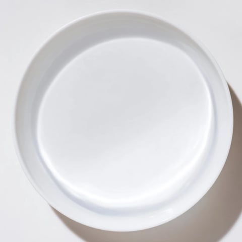 A clear glass of water sits beside a vibrant, colorful dinner plate.  