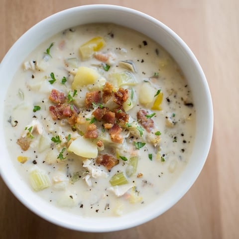 A steaming bowl of New England Clam Chowder, creamy and packed with bacon and tender clams.