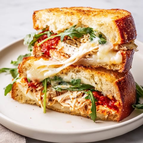 Golden crust Leftover Pizza Chicken Sandwich with melted cheese, arugula, and juicy chicken filling.