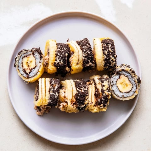 Vibrant Oreo Cookie Sushi Rolls coated in coconut, ready to dip in rich chocolate soy sauce.