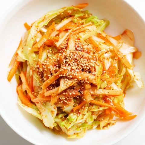 Stir-fried Hot and Sour Cabbage in a wok, showcasing crisp green leaves tossed in a glossy, spicy, and tangy sauce with fresh ginger and garlic.