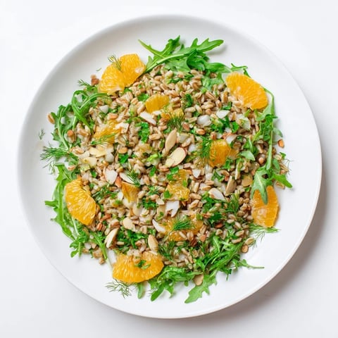Farro salad with fennel, oranges, and almonds in a white bowl, dressed in citrus vinaigrette and garnished with fresh parsley.  