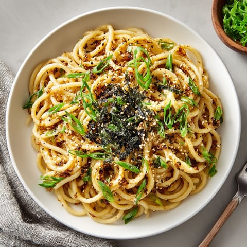 A bowl of noodles with vegetables and seasoning.