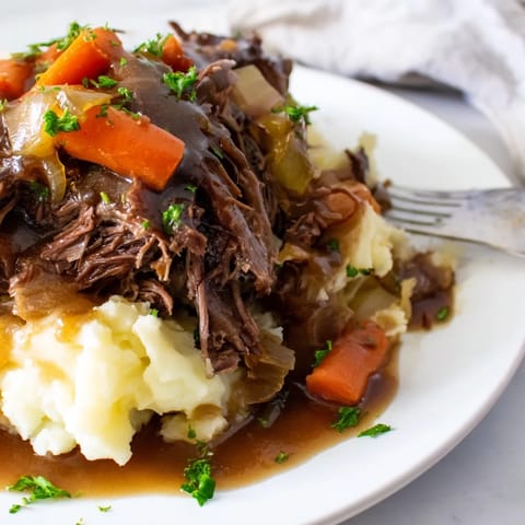 Tender beef pot roast slowly cooked to perfection with rich gravy and veggies.  