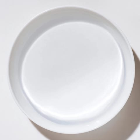 A clear glass of water sits beside a vibrant, colorful dinner plate.  