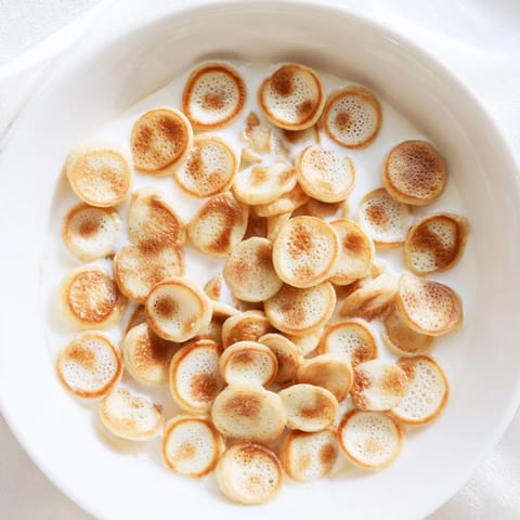 Miniature pancake cereal: Fluffy, perfectly cooked golden bites, ready with fresh fruit and milk.