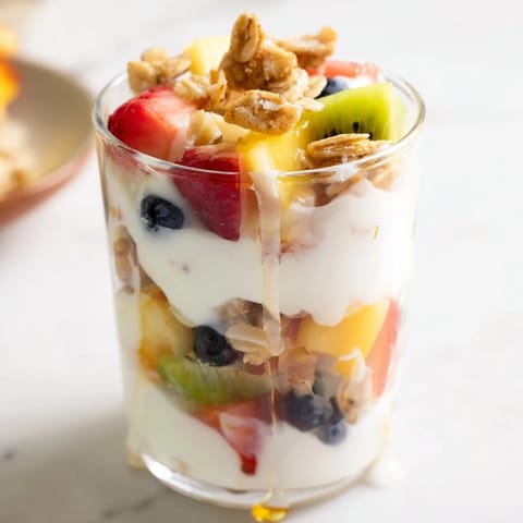 Freshly layered yogurt parfait featuring creamy yogurt, ripe fruit, and golden granola.