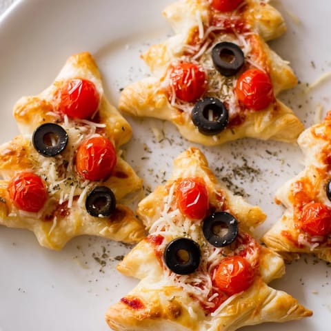 Enjoy a close-up image of flaky Puff Pastry Christmas Tree Pizza Bites with vibrant toppings and olive accents.