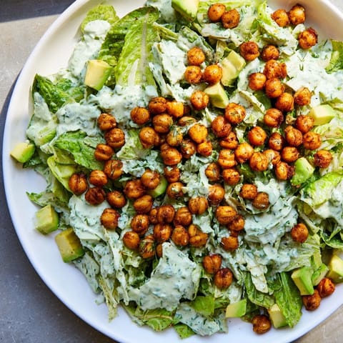 Freshly prepared Green Goddess Salad, boasting a medley of vibrant greens, finished with crunchy, golden chickpeas.