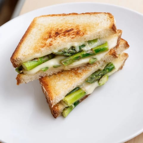 A steaming Asparagus & Brie Grilled Cheese sandwich, showcasing the gooey Brie and char-grilled asparagus.