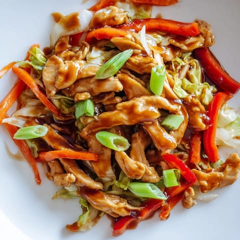 A close-up of colorful Chicken Cabbage Stir-Fry with vibrant red peppers, carrots, and green onions in an aromatic garlic-ginger glaze.  
