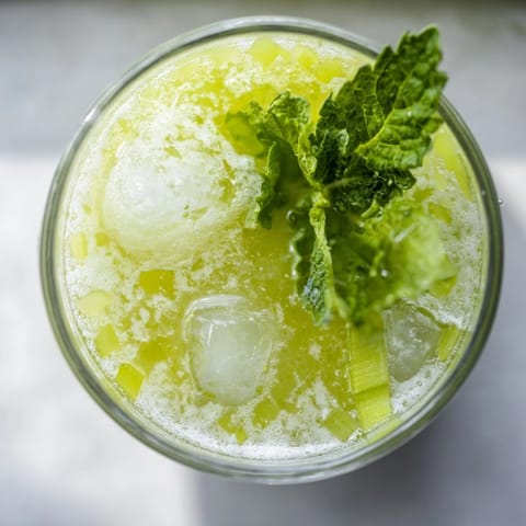 Bright green Celery Ginger Lemon Juice in a clear mason jar, garnished with celery stalks and lemon wheels, served over ice for a refreshing drink.