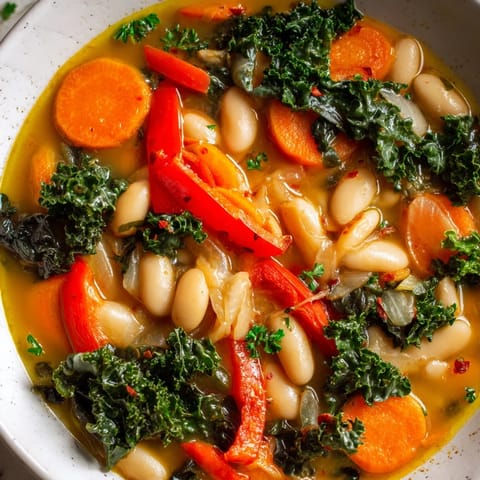 Close-up view of Mediterranean White Bean Stew served with lemon wedges, highlighting vibrant red bell pepper and a drizzle of olive oil.  