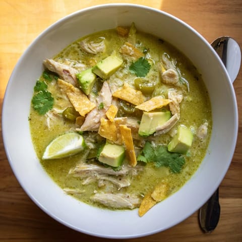A warm bowl of Creamy Chicken Tortilla Soup garnished with cilantro and fresh lime wedges.