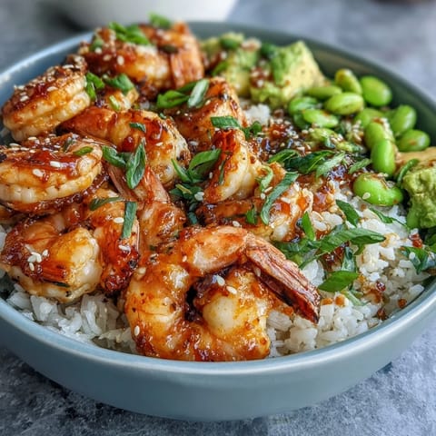 Fresh shrimp poke bowl with juicy mango, edamame, and avocado, drizzled with savory soy-ginger sauce and sesame seeds.