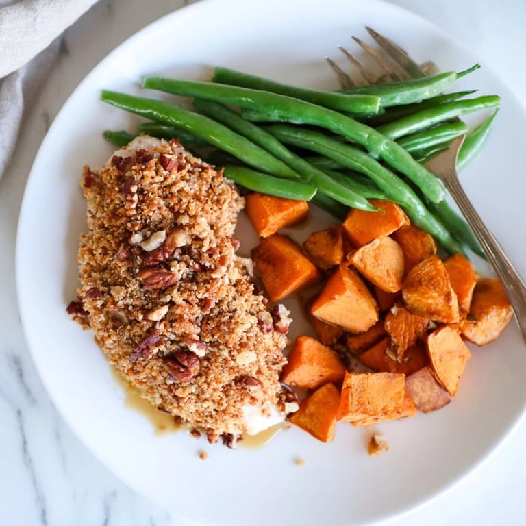 Crisp Pecan Chicken on a sheet pan alongside green beans ready for family meal night.