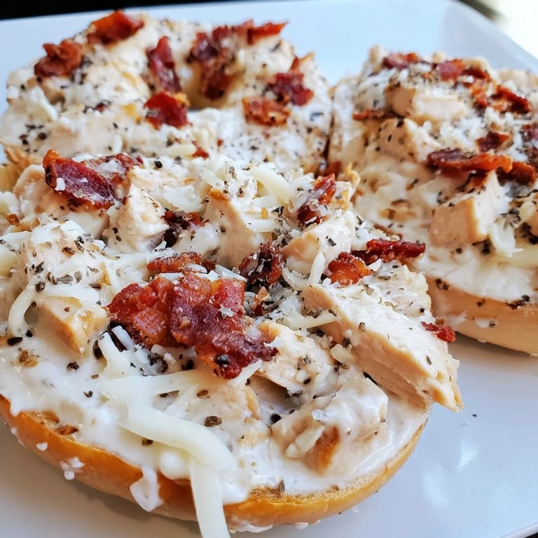 Irresistible Alfredo Chicken Bacon Pizza Bagels fresh from the oven, garnished with parsley.