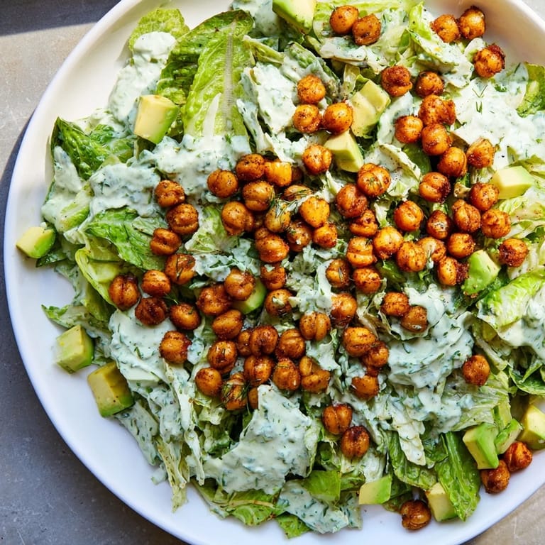 Freshly prepared Green Goddess Salad, boasting a medley of vibrant greens, finished with crunchy, golden chickpeas.