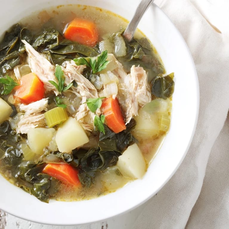 Overhead view of a hearty pot of Collard Greens, Chicken and Vegetable Soup, featuring carrots, celery, potatoes, and wilted collard greens.